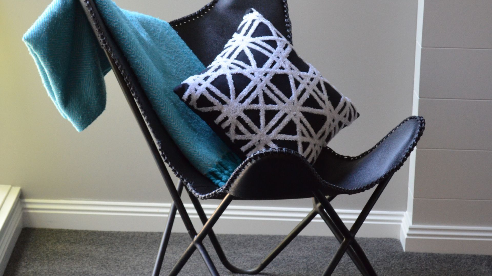 Une chaise avec un coussin à motifs géométriques et un tissu turquoise drapé dessus.