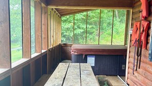 Eine Holzhütte mit Picknicktisch, Bänken und Sitzgelegenheit.