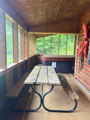 A wooden cabin with a picnic table, benches, and a bench seat.