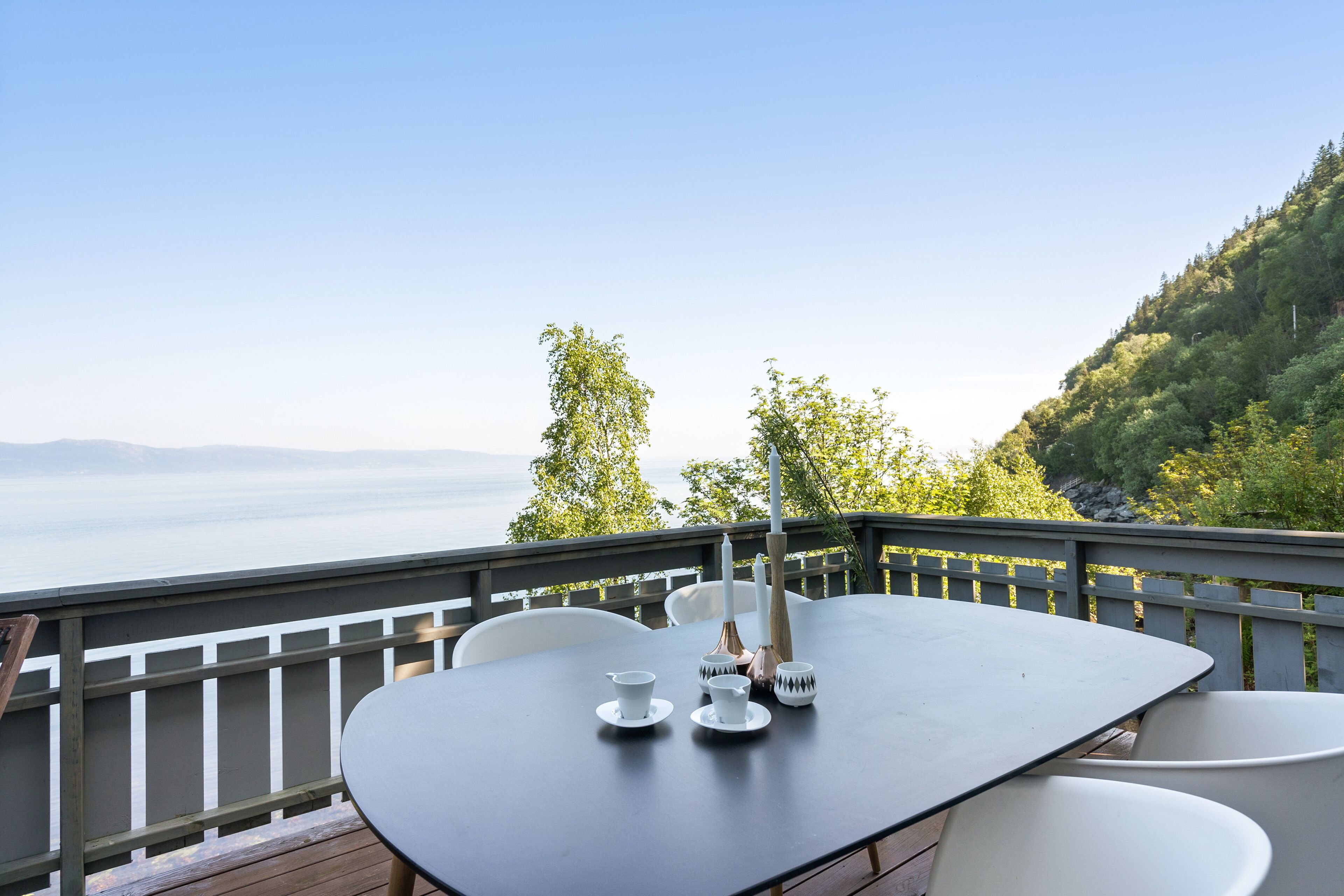 Ein Tisch im Freien mit Blick auf das Meer und die Hügel.