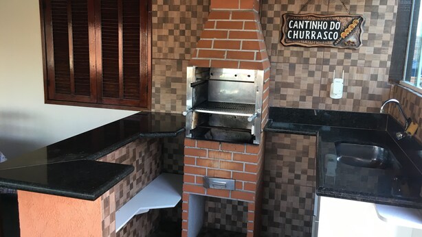 Una cocina con horno de ladrillo, una ventana con contraventanas de madera y un letrero que dice "Cantinho do Churrasco".