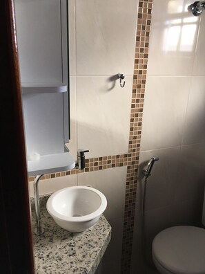 Een badkamer met een wit wastafel, een spiegel en een douche.