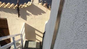 Una escalera conduce a la entrada de un edificio, con barandilla blanca y un panel solar en un poste.