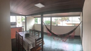 Un comedor con una mesa para dos, una hamaca y ventanas grandes.