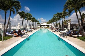 A pool with lounge chairs and palm trees.