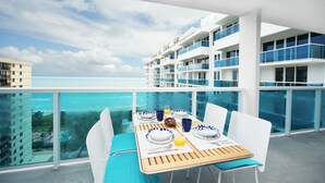 A balcony with a table set for breakfast, overlooking a clear blue sea and a resort area. - Incredible Ocean Views! 2 BR/2.5 Bath, On Top of 1 Hotel! 15th Flr, 4 Pools! (Miami Beach)