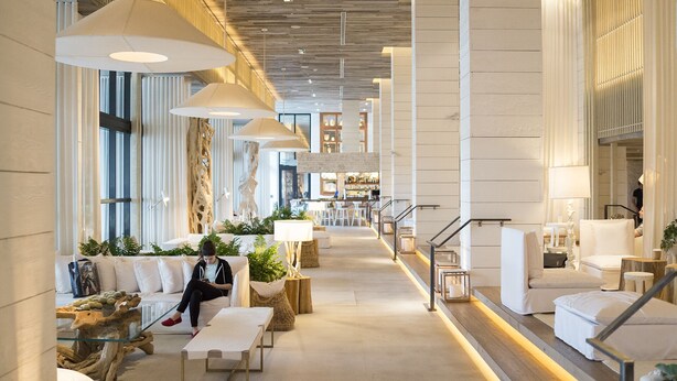 A modern hotel lobby with a central bar area, seating arrangements, and large pendant lights. - Incredible Ocean Views! 2 BR/2.5 Bath, On Top of 1 Hotel! 15th Flr, 4 Pools! (Miami Beach)