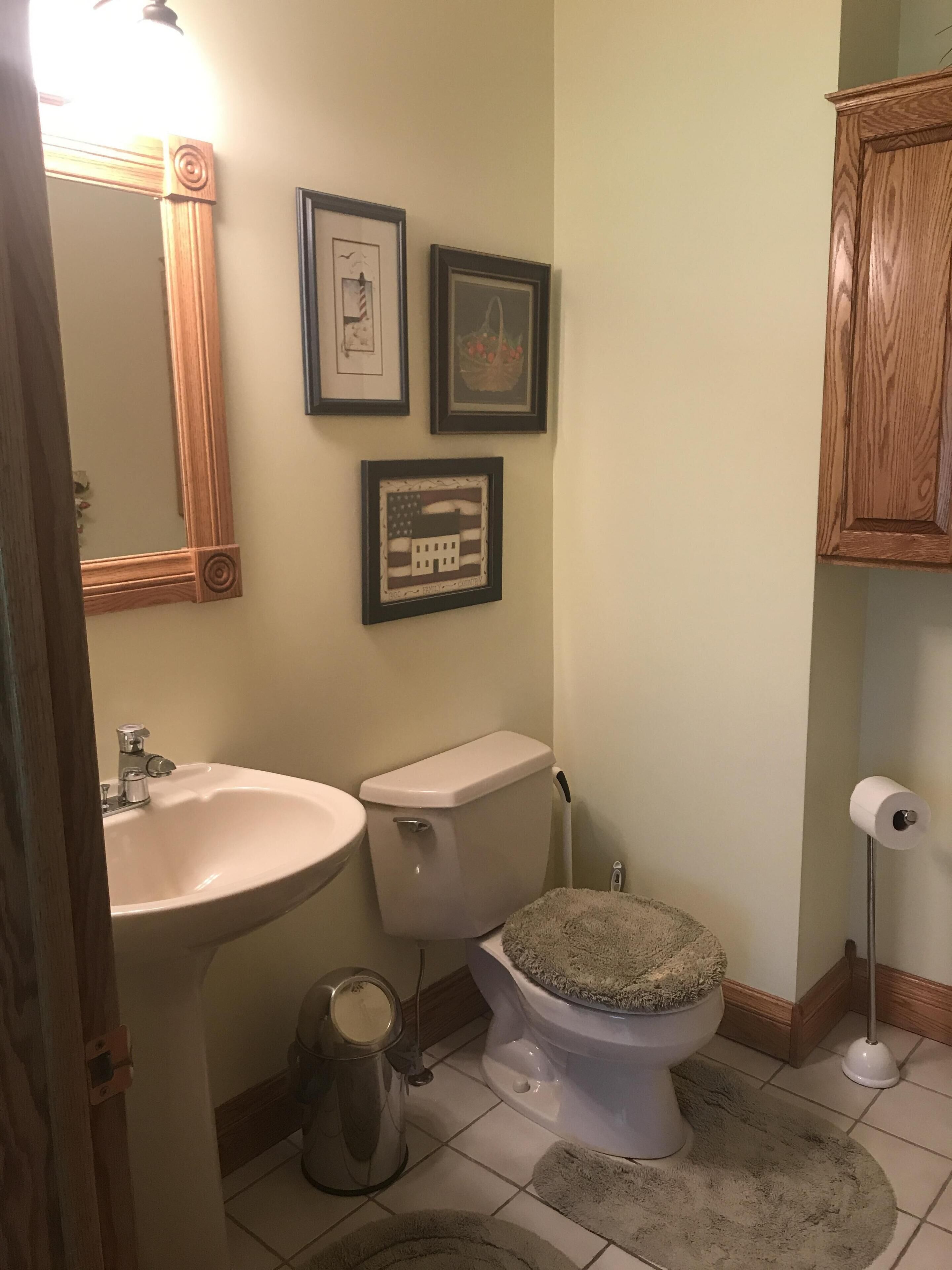 Un bagno con lavandino, WC e quadri appesi alle pareti.