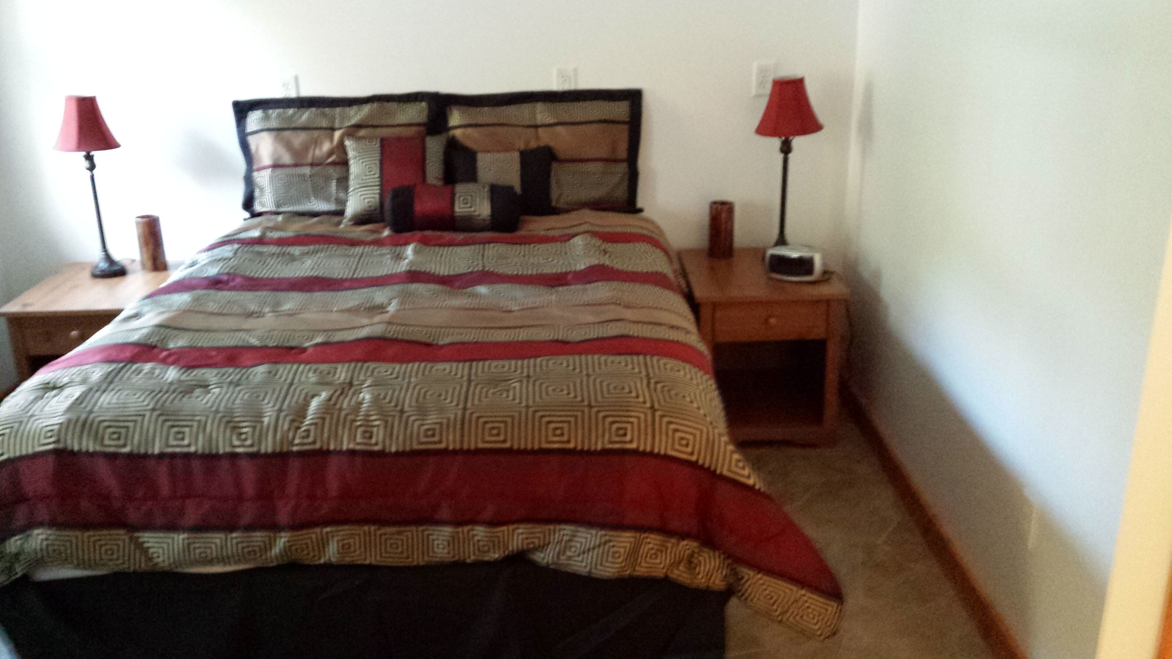 Un dormitorio con una cama, dos mesitas de noche y dos lámparas.
