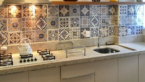 Una cocina con salpicadero de azulejos, estufa a gas, lavamanos y encimera.