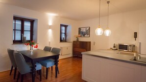 Uma cozinha moderna com ilha central, piso de madeira e iluminação pendente.