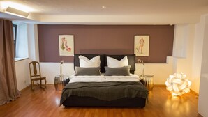 Quarto com uma cama grande, duas mesas de cabeceira, uma cadeira e um abajur decorativo.