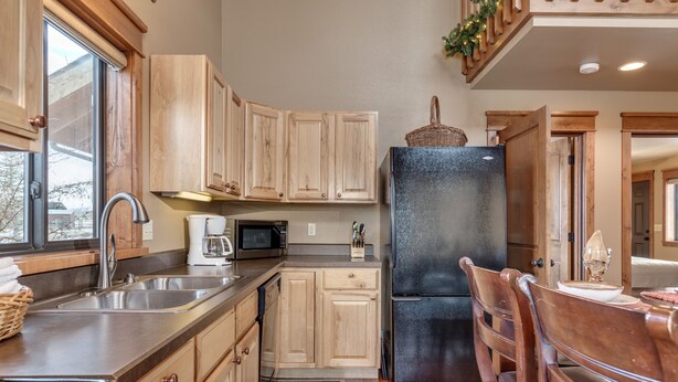 A kitchen with wooden cabinets, a black refrigerator, a microwave, and a sink.