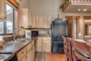 A kitchen with wooden cabinets, a black refrigerator, a microwave, and a sink.