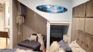 A bedroom with a bed, a small seating area, a chandelier, and a sign that says "Wonderlust".