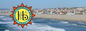 A beach with a logo of Hermosa Beach, 1907, and a coastal town in the background.