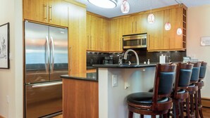 Eine Küche mit Holzausstattung, Edelstahlgeräten und einer Bar mit Sitzgelegenheiten.