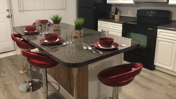A kitchen with a granite countertop, black refrigerator, white cabinets, and a microwave. - Large Home Accommodates Up To 15 In Niagara USA (Niagara Falls)