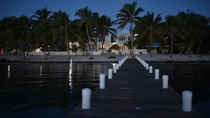 A wooden pier leading to a beachfront property with palm trees and a white fence. - Live & Sleep over the Sea!! ** Glamping in Paradise** (San Pedro)