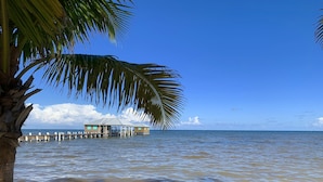 A beachside structure with a roof, wooden deck, and a view of the ocean. - Live & Sleep over the Sea!! ** Glamping in Paradise** (San Pedro)