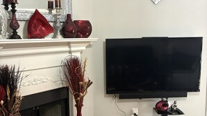 Una sala de estar con chimenea, televisor de pantalla plana y elementos decorativos.