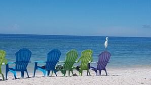 Een rij kleurrijke Adirondack-stoelen gericht op de oceaan.