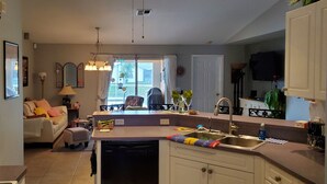 Een keuken met een vaatwasser, een spoelbak en een eethoek met een tafel en stoelen.