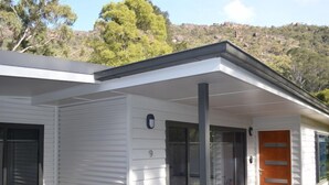 Una casa moderna con un portico coperto, rivestimento bianco e una porta in legno.