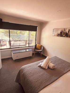 Une chambre à coucher comprenant un lit, une chaise, un bureau et une fenêtre donnant sur un balcon extérieur.