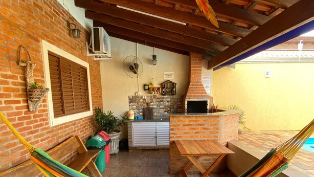 Een terras met een hangmat, houten meubels, een bakstenen muur en een betegelde vloer.