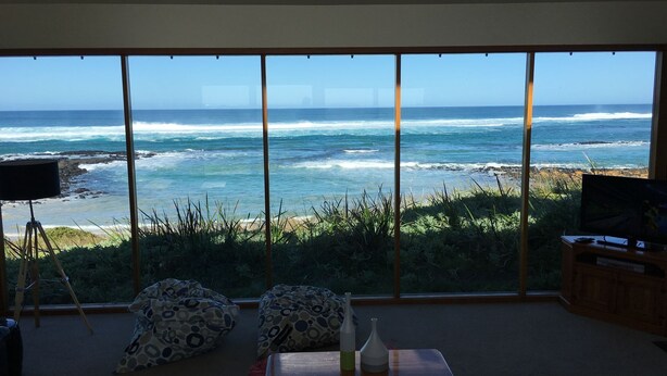 A room with a large window overlooking the ocean, a tripod with a camera, and a television on a wooden cabinet. - Bluestone Bay - Port Fairy (Port Fairy)