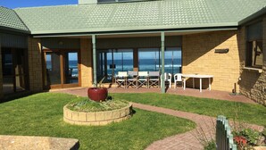 A patio area with a view of the ocean, outdoor seating, and a planter. - Bluestone Bay - Port Fairy (Port Fairy)