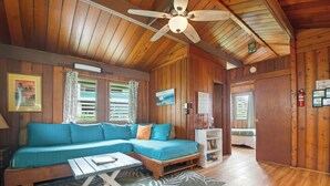 Ein Holzblockhaus-Innenraum mit einer Couch, einem kleinen Tisch und einem Deckenventilator.
