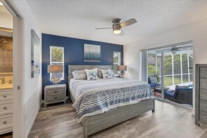 A bedroom with a bed, two bedside tables, a ceiling fan, and a view of the outdoors through a sliding glass door. - Relax in our PRIVATE Pool at Water View Villa (Venice)