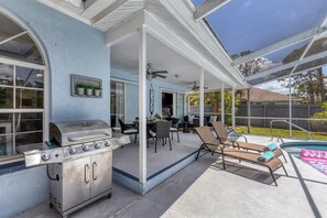 A covered patio with a grill, outdoor seating, and a view of a backyard. - Relax in our PRIVATE Pool at Water View Villa (Venice)