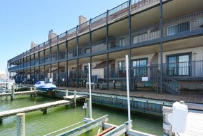 Un edificio a più piani fronte mare con balconi, un molo e una barca.