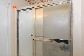 Un baño con cabina de ducha de vidrio y puerta blanca.