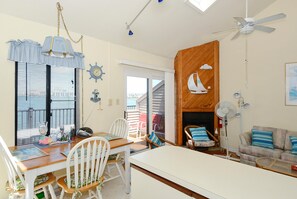 Una stanza con tavolo e sedie da pranzo, camino, ventilatore a soffitto e vista sull'esterno.