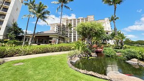 A hotel with a pool, palm trees, and a well-maintained garden.