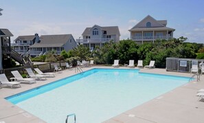 A rectangular swimming pool with lounge chairs and a staircase leading to a building.