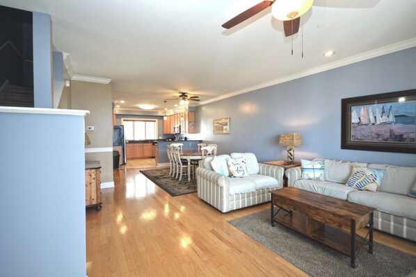 A spacious living room with a sofa, coffee table, and a dining area with chairs.