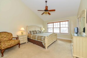 A bedroom with a bed, nightstand, chair, dresser, and a ceiling fan.
