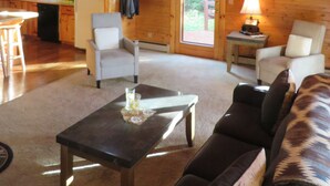 A spacious cabin with a high ceiling, wooden walls, a dining area, a living room with a sofa, and a kitchen. - SUNDOWN ON MOOSEHEAD LAKE - PLEASE READ THE ENTIRE DESCRIPTION  BEFORE BOOKING. (Greenville)