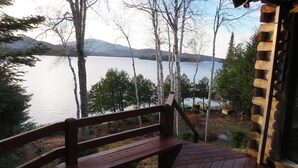 A wooden deck with a bench overlooking a lake, surrounded by trees and mountains. - SUNDOWN ON MOOSEHEAD LAKE - PLEASE READ THE ENTIRE DESCRIPTION  BEFORE BOOKING. (Greenville)