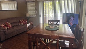 Un salon avec un canapé marron, une table à manger en bois et un ventilateur de plafond.