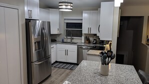 Una cocina moderna con electrodomésticos de acero inoxidable, armarios blancos y encimera de granito.
