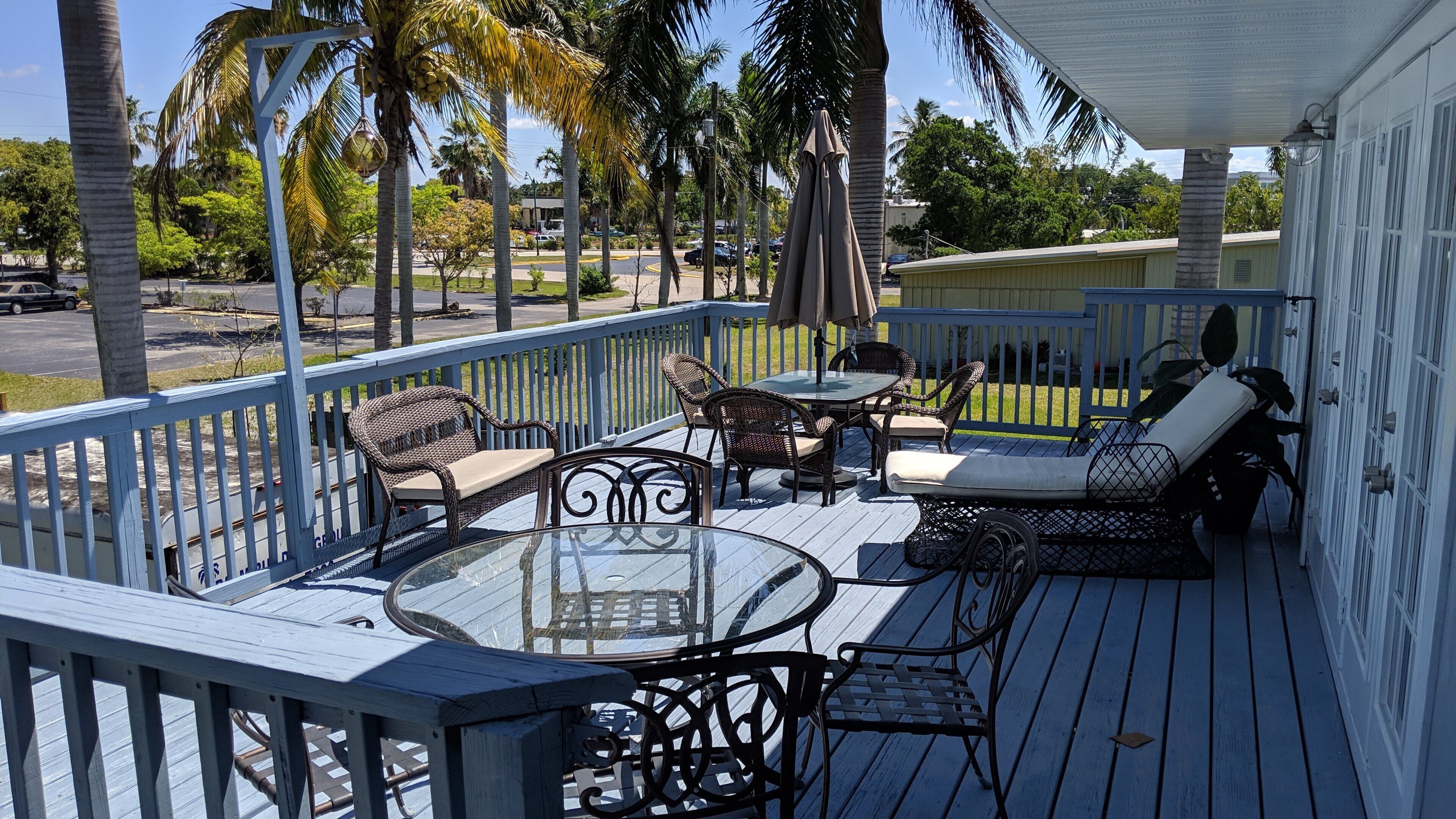 Une terrasse extérieure couverte, dotée d'une table en verre, de chaises en osier et d'un fauteuil de relaxation.