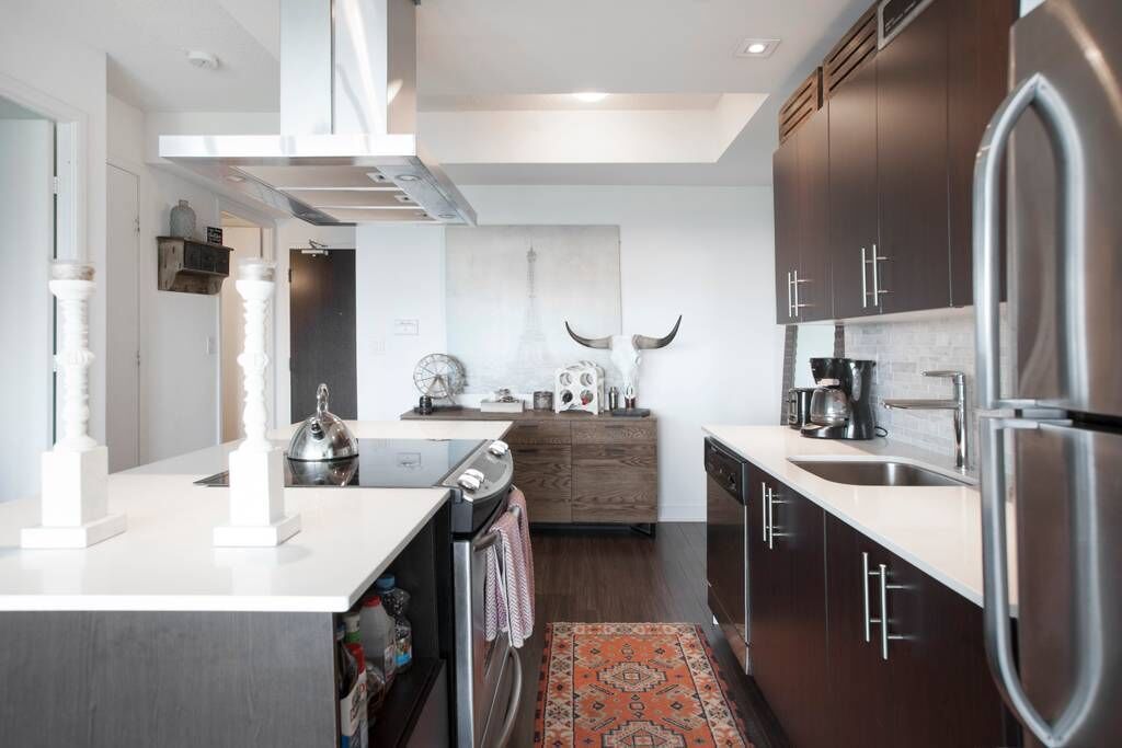 A modern kitchen with dark wooden cabinets, stainless steel appliances, and a central island with a white countertop.