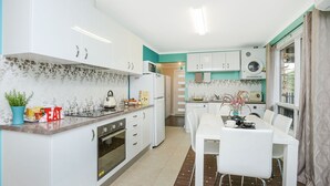 A modern kitchen with white cabinets, a built-in oven, and a dining area with a table and chairs.