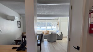 Una sala moderna con sofá, sillón y una mesa de comedor con una silla.